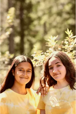 Dos chicas sonriendo a cámara en un bosque