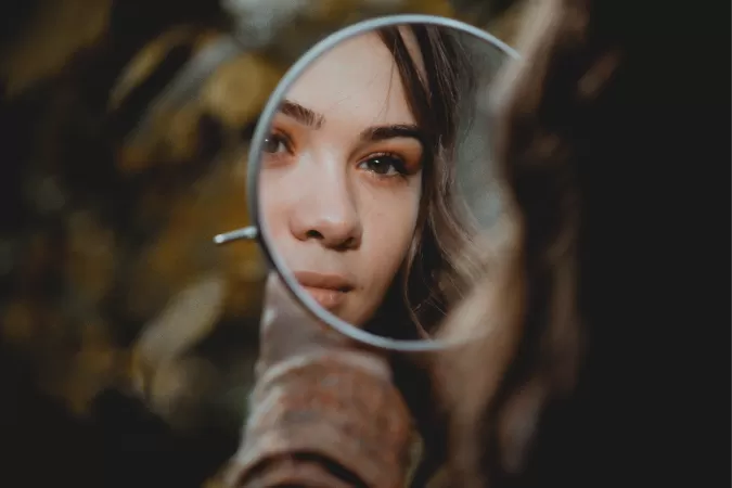 La cara de una niña reflejada en un espejo de mano redondo